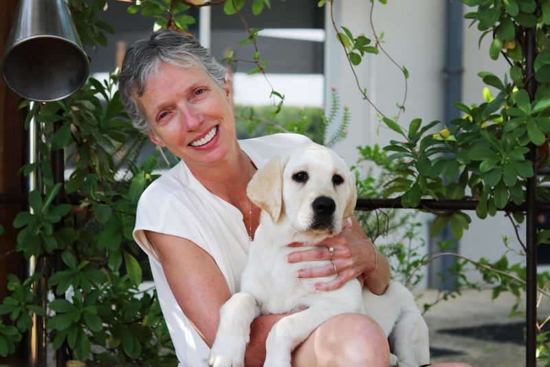 A woman holding a puppy smiling