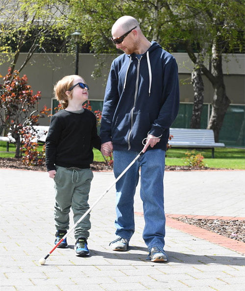 A father and son, father has a white cane